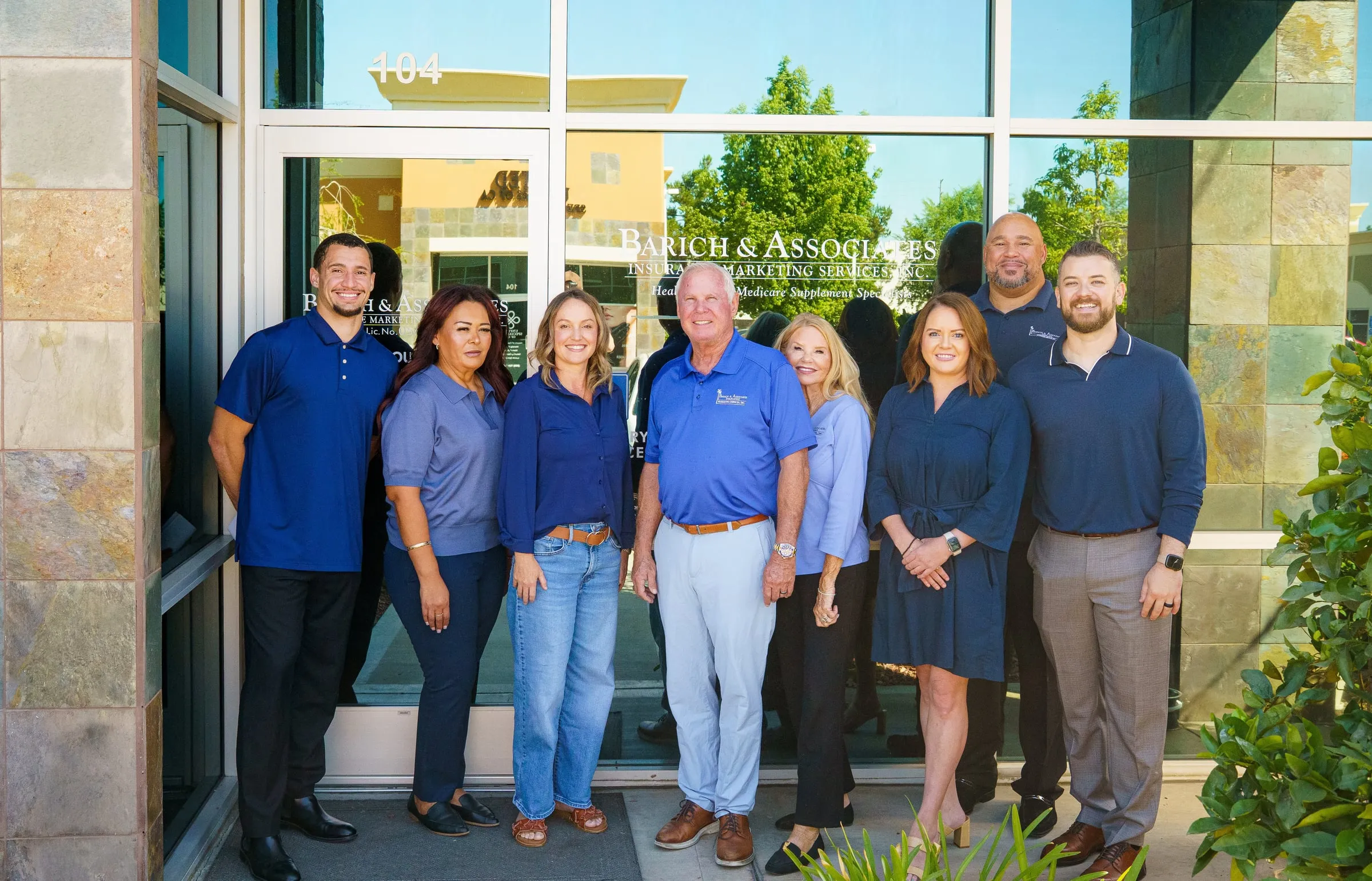 The Barich & Associates team standing together outside the Redlands office, under the firm's sign.
